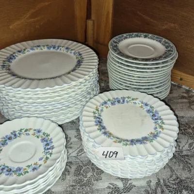 Sale Photo Thumbnail #721: Stacks of vintage floral porcelain dinnerware featuring blue flower wreaths and scalloped edges.