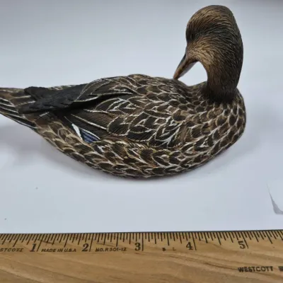 Sale Photo Thumbnail #250: Finely detailed hand-painted resin or carved duck decoy figurine, depicting a preening hen duck with realistic feather texture.