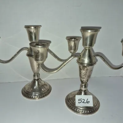 Sale Photo Thumbnail #908: Pair of vintage silver-plated three-light candelabras with gadrooned details and curved arms, showing minor surface tarnish and wear.