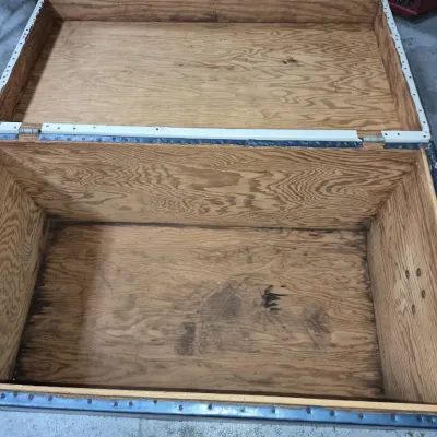 Sale Photo Thumbnail #8: Open vintage storage trunk featuring a plywood interior and metal trim along the edges.