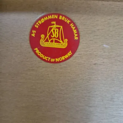 Sale Photo Thumbnail #179: Maker's mark sticker for A/S Strømmen Bruk Hamar, indicating a mid-century Scandinavian furniture piece made in Norway.