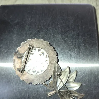 Sale Photo Thumbnail #852: Underside of two vintage sterling silver brooches resting on a digital scale, displaying pin mechanisms and maker's hallmarks.