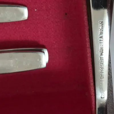 Sale Photo Thumbnail #704: Close-up of stainless steel cutlery set by Present Marcella, made in Taiwan, resting in a red felt-lined storage box.