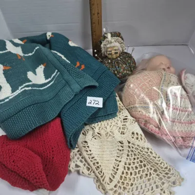 Sale Photo Thumbnail #462: Collection of crafting items, including a teal knit duck blanket, crocheted pieces, a novelty grandmother pin cushion, and a bagged composite doll.