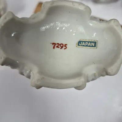Sale Photo Thumbnail #382: Underside of a vintage ceramic figurine featuring a red stamped item number 7295 and an original foil 'JAPAN' label.