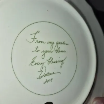 Sale Photo Thumbnail #713: Underside of a decorative ceramic plate with a handwritten inscription reading "From my garden to your home. Every blessing, Valerie 2009."