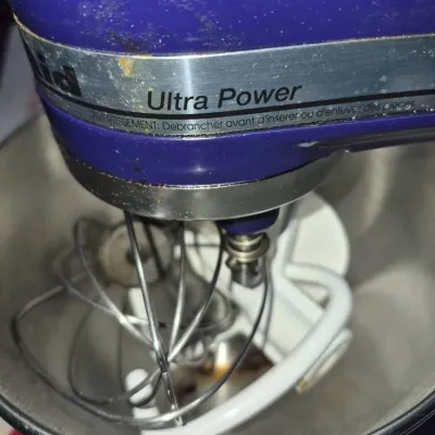 Sale Photo Thumbnail #65: Cobalt blue KitchenAid Ultra Power stand mixer with stainless steel mixing bowl and attached whisk, featuring minor wear along the chrome band.