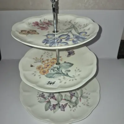 Sale Photo Thumbnail #629: Three-tier porcelain serving tray featuring botanical floral patterns with irises, butterflies, and sweet peas on scalloped plates with a silver-tone metal center spindle.