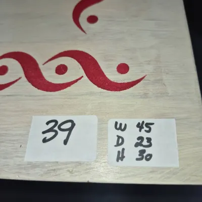Sale Photo Thumbnail #61: Close-up of a whitewashed wooden surface featuring a red wave motif, labeled lot #39 with dimensions W 45, D 23, H 30.