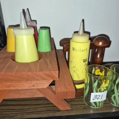 Sale Photo Thumbnail #559: Vintage miniature wooden picnic table condiment set featuring squeeze bottles, salt and pepper shakers, and a pair of yellow floral printed shot glasses.
