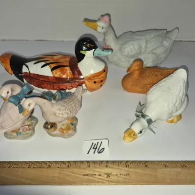Sale Photo Thumbnail #247: Collection of six ceramic and porcelain duck and goose figurines in various styles and sizes, accompanied by a wooden ruler.