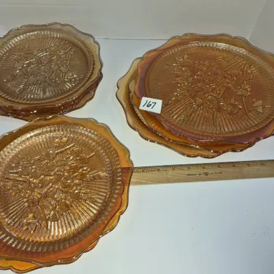 Sale Photo Thumbnail #288: Set of marigold carnival glass plates featuring embossed floral and wheat designs, in varied sizes.