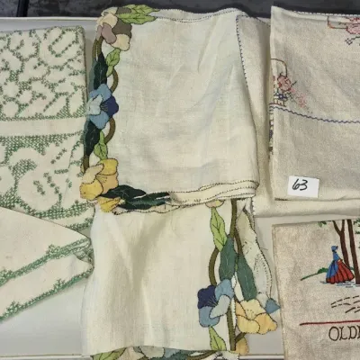 Sale Photo Thumbnail #96: Collection of vintage embroidered and cross-stitched linens, including a souvenir 'Olde Williamsburg' cloth, floral appliqué pieces, and green cross-stitched napkins.