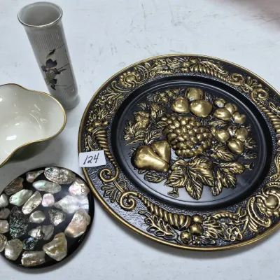 Sale Photo Thumbnail #203: Collection of decorative home accents, including a large embossed metallic fruit-motif platter, an abalone shell inlay trivet, a small floral vase, and a gilded ceramic bowl.