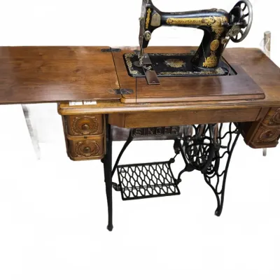 Sale Photo Thumbnail #186: Antique Singer treadle sewing machine set in an ornate wood cabinet with side drawers and a drop-leaf extension.