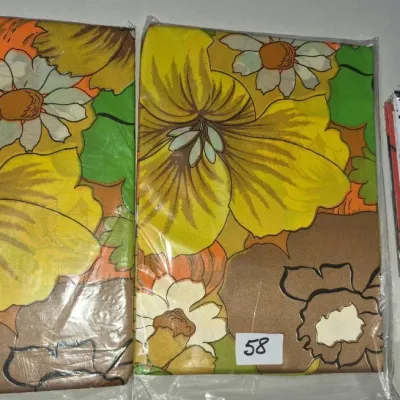 Sale Photo Thumbnail #91: Vintage 1970s bedding including a set with a bold yellow and orange floral print alongside a packaged B. Kliban Cat pillowcase set by Burlington Caress.