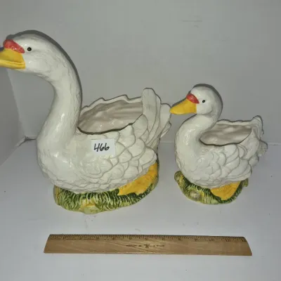 Sale Photo Thumbnail #803: Pair of vintage glazed ceramic goose-shaped planters in white with yellow bills and green bases, accompanied by a ruler for scale.