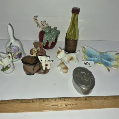 Sale Photo Thumbnail #706: Collection of vintage miniature trinkets and figurines, including porcelain dog and cat statuettes, a ceramic bell, a butterfly dish, and a small metal box.