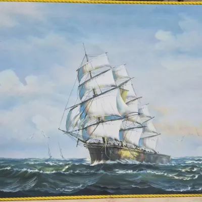 Sale Photo Thumbnail #498: Framed nautical oil painting depicting a tall sailing ship at sea, finished with a yellow rope-style border.