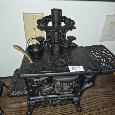 Sale Photo Thumbnail #566: Miniature Crescent cast iron cookstove set complete with pots, pans, and kettle accessories.