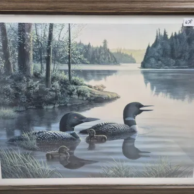Sale Photo Thumbnail #471: Framed wildlife art print depicting a family of loons swimming on a serene lake, housed in a wood-tone frame.