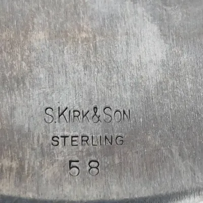 Sale Photo Thumbnail #904: Maker's mark closeup on sterling silver piece, stamped "S. KIRK & SON STERLING 58" on brushed metal surface.