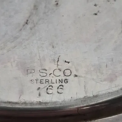 Sale Photo Thumbnail #915: Close-up detail of a hallmark on sterling silver, stamped with 'P.S. CO STERLING 166'.