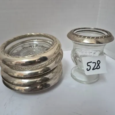 Sale Photo Thumbnail #912: Vintage glass and silver-toned coaster set with starburst base patterns, alongside a small matching glass vessel featuring a decorative metal rim.