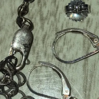 Sale Photo Thumbnail #860: Selection of sterling silver jewelry findings, including a lobster claw clasp attached to a chain extender, a pair of leverback earring hooks, and an earring clutch back.
