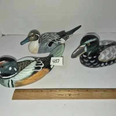 Sale Photo Thumbnail #790: Set of three hand-painted wooden duck decoys with detailed feather carving, shown alongside a wooden ruler for scale.