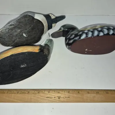 Sale Photo Thumbnail #791: Set of three vintage hand-carved and painted wooden duck decoys shown from the underside, displayed with a 12-inch ruler for scale.