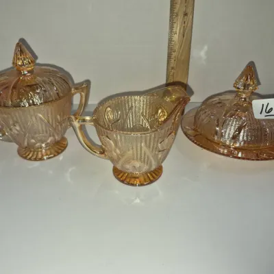 Sale Photo Thumbnail #287: Vintage marigold carnival glass tableware set, including a lidded sugar bowl, cream pitcher, and a covered butter dish in Iris and Herringbone pattern.