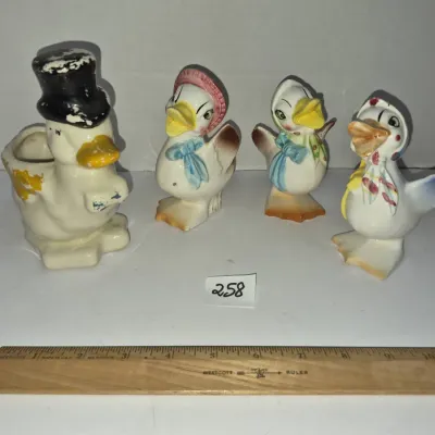 Sale Photo Thumbnail #441: Collection of vintage ceramic duck figurines, including salt and pepper shakers and a small planter, featuring anthropomorphic designs with hats and scarves and paint wear throughout.