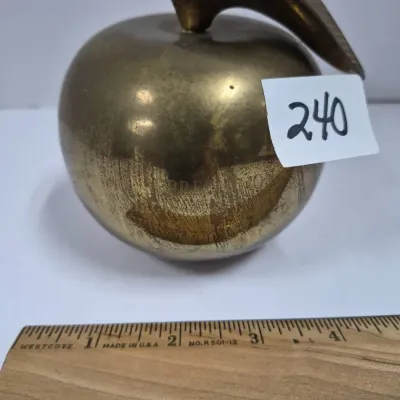 Sale Photo Thumbnail #411: Vintage brass apple-shaped paperweight or figurine with leaf detail, showing light patina and wear, measured alongside a ruler.