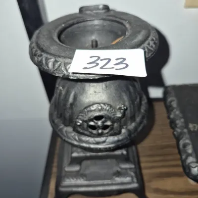Sale Photo Thumbnail #564: Vintage cast iron miniature potbelly stove-style match holder or toothpick dispenser featuring detailed ornate relief accents.