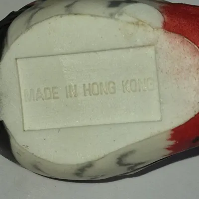 Sale Photo Thumbnail #432: Underside of a vintage plastic bird figurine displaying an embossed "MADE IN HONG KONG" mark.