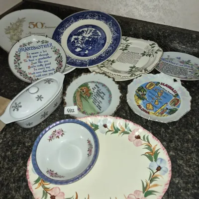 Sale Photo Thumbnail #710: Collection of vintage decorative plates and serving dishware, including Blue Willow china, souvenir plates, and a covered casserole.
