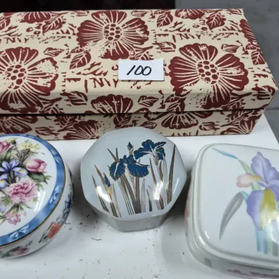 Sale Photo Thumbnail #156: Collection of decorative trinket boxes, including three floral porcelain lidded containers and a fabric-covered rectangular box.