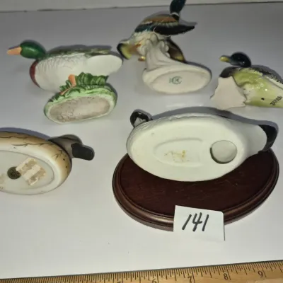 Sale Photo Thumbnail #239: Collection of five vintage ceramic duck and waterfowl figurines, shown turned over to reveal maker marks and bases, including one mounted on an oval wooden plinth.