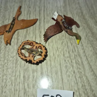 Sale Photo Thumbnail #876: Trio of vintage novelty brooches featuring two flying duck motifs and a carved walnut shell pin with standard pin-back clasps.