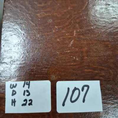 Sale Photo Thumbnail #174: Close-up of a dark wooden furniture surface showing moderate wear, featuring labels with dimensions (W 14, D 13, H 22) and lot number 107.