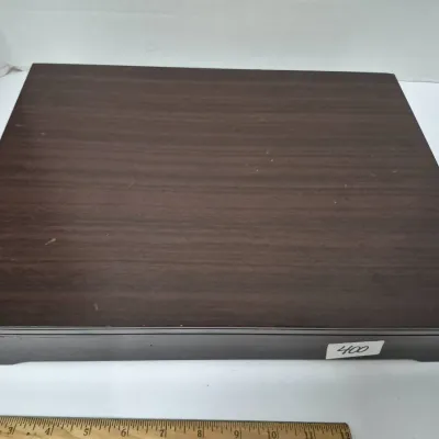 Sale Photo Thumbnail #705: Rectangular dark wood storage box with a flat lid and contoured base, featuring minor surface wear along the bottom corner.