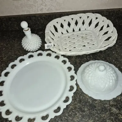 Sale Photo Thumbnail #719: Four-piece collection of white milk glass items including a lattice-work bowl, a hobnail perfume bottle, a heart-reticulated tray, and a covered butter dish.
