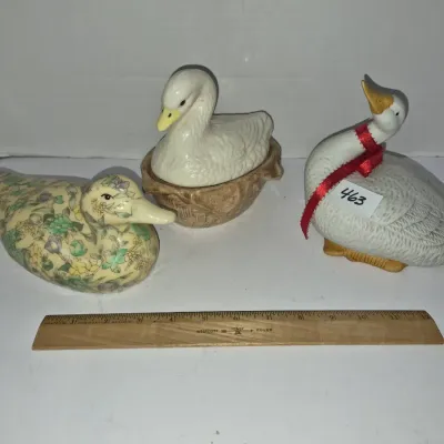 Sale Photo Thumbnail #799: Trio of vintage ceramic waterfowl figurines, including a floral duck, a swan in a basket base, and a goose with a red ribbon neck tie.