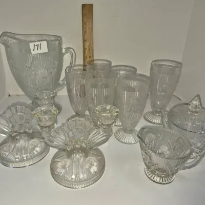 Sale Photo Thumbnail #295: Vintage Jeanette Glass Co. Iris and Herringbone clear pressed glass set, including a pitcher, goblets, candlesticks, and cream and sugar bowl.