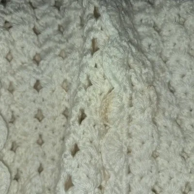 Sale Photo Thumbnail #70: Off-white handmade crocheted blanket or shawl featuring an openwork shell pattern and scalloped edging, showing a minor discoloration stain near the center crease.