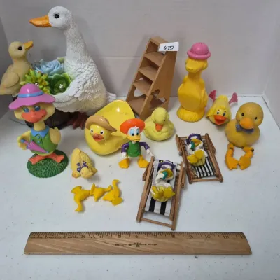 Sale Photo Thumbnail #815: Collection of duck-themed decorative figurines and novelties, including resin, ceramic, and plastic pieces alongside small wooden accessory furniture.
