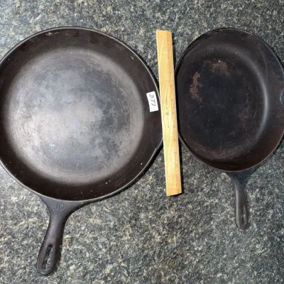 Sale Photo Thumbnail #654: Pair of vintage cast iron skillets, including a size No. 10 pan, showing natural wear and patina.