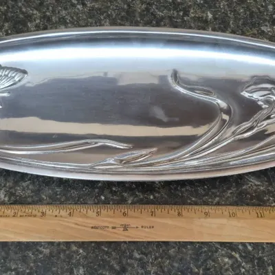 Sale Photo Thumbnail #658: Elongated aluminum serving tray featuring embossed butterfly and floral iris motifs in Art Nouveau style, measuring approximately 12 inches long.