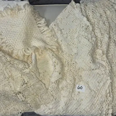 Sale Photo Thumbnail #93: Collection of vintage white and cream crochet blankets and lace bedspreads, featuring fringed edges and openwork patterns.